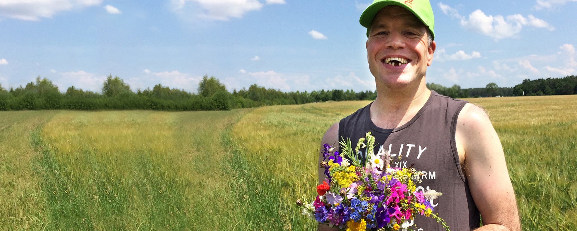 Augustinum Ehrenamtliche Ein Bewohner steht im Freien und hält einen Blumenstrauß