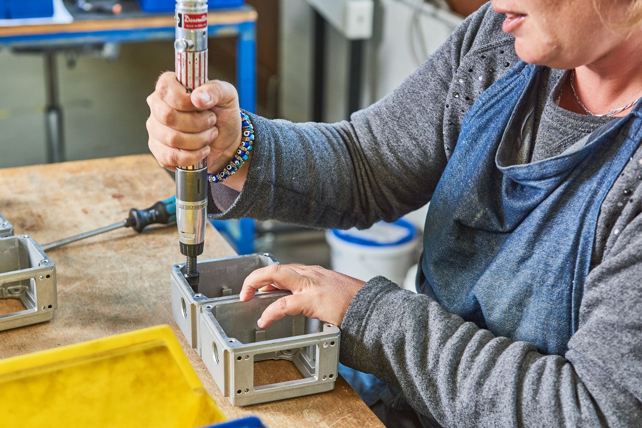Eine Klient*in montiert eine Schraube an einem Metallteil
