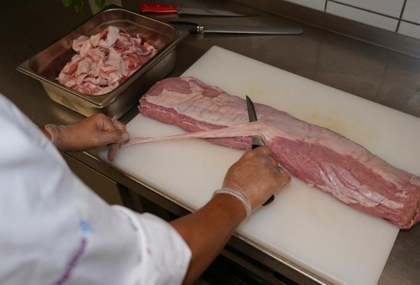 Fleisch parieren Ein*e Koch*Köchin pariert ein großes Stück Fleisch