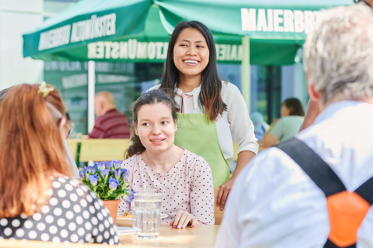 Gemeinsame Mahlzeiten Eine Gruppe von Bewohner*innen sitzen an einem Tisch im Freien