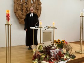 Pfarrerin vor Altar mit Erntedank-Gaben