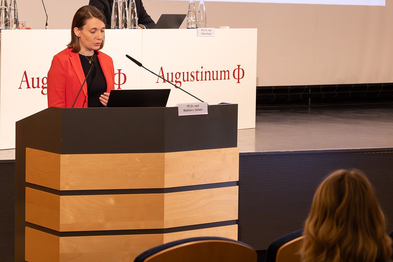 Augustinum Klinik Symposium von Jeinsen Die Referentin Dr. von Jeinsen steht an einem Rednerpult und spricht in das Mikrofon