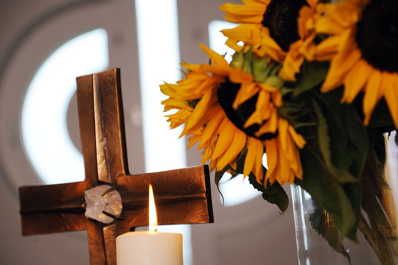 In den Augustinum Seniorenresidenzen wird viel Wert auf Seelsorge gelegt- unabhängig von einer christlichen Konfession. Kreuz, Kerze und ein Strauß Sonnenblumen