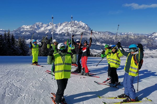 Augustinum Samuel-Heinicke-Realschule Wintersportwoche Ein Gruppenfoto von Schüler*innen beim Skifahren, wobei jeder seine/ihre Skistöcke in die Luft hebt