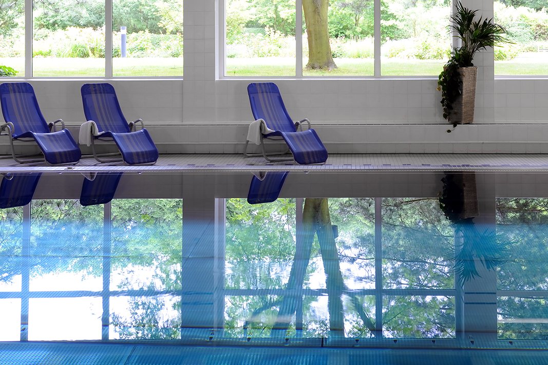 Entspannung und Wellness im hauseigenen Schwimmbad mit Sauna. Schwimmbecken mit Liegestühlen am Rand