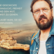 Bärtiger Mann mit Brille blickt geradeaus hinter ihm die Umrisse einer Stadt am Meer Bärtiger Mann mit Brille blickt geradeaus hinter ihm die Umrisse einer Stadt am Meer