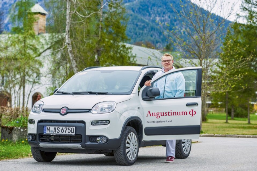 Ein Mitarbeiter des ambulanten Pflegedienstes steht an der offenen Tür eines Autos