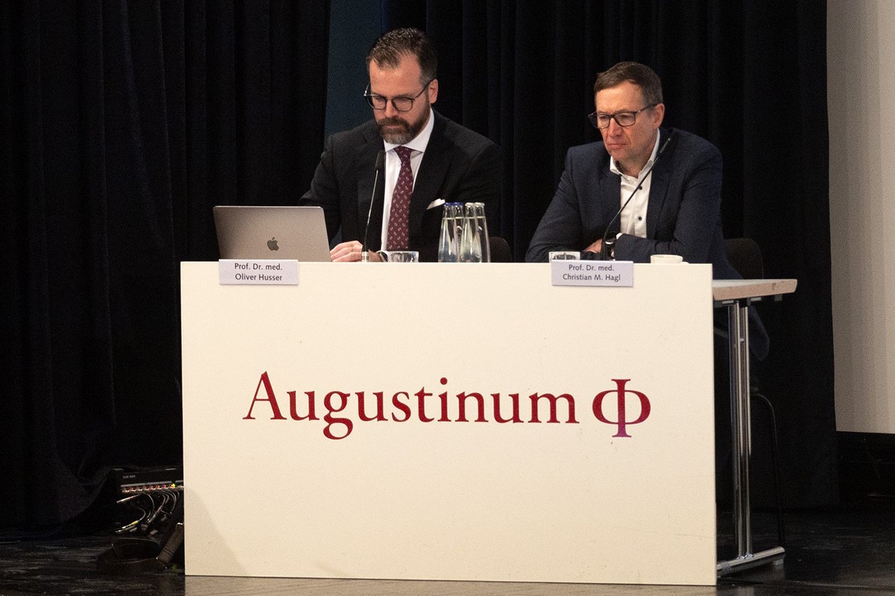 Augustinum Klinik Symposium Dr. Husser und Dr. Hagl Prof. Dr. Husser der Augustinum Klinik und Prof. Dr. Hagl des LMU Klinikum sitzen bei der Veranstaltung auf der Bühne