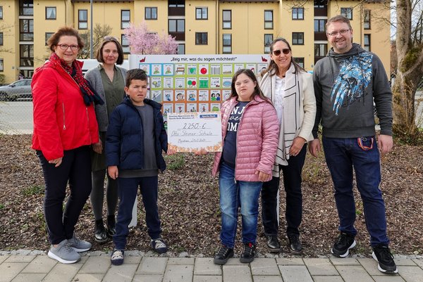 Augustinum Spenden Kommunikationstafeln Zwei Schüler*innen der Otto-Steiner-Schule, die einen Spendenscheck halten, und vier Erwachsene stehen vor einer Kommunikationstafel