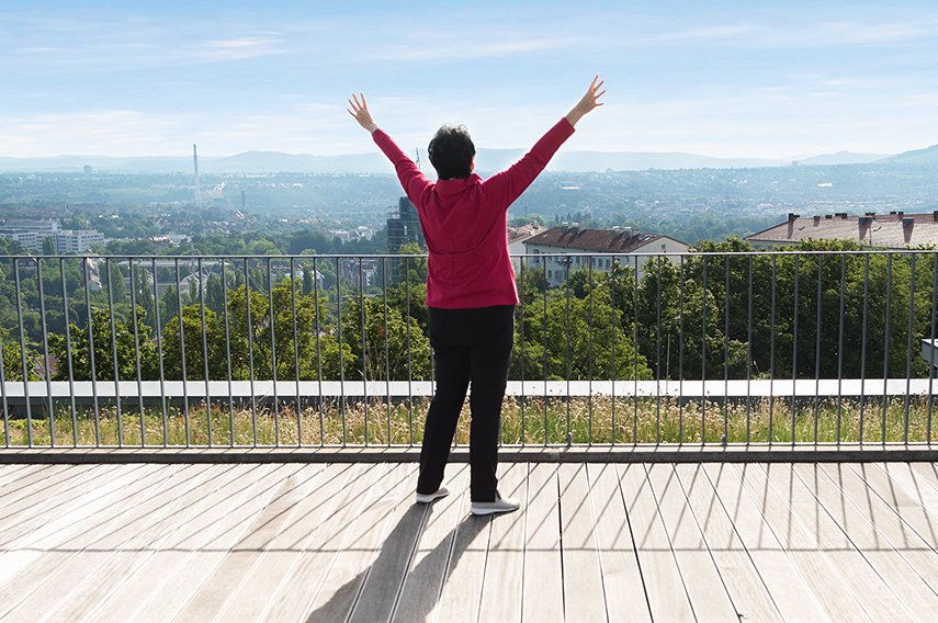 Qi Gong Frau mit ausgestreckten Armen auf einer Dachterrasse