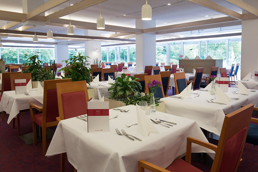 Das Restaurant ist zentraler Treffpunkt für die Bewohner. Hier werden täglich mehrere Mittagsmenüs zur Auswahl angeboten. Restaurant mit gedeckten Tischen