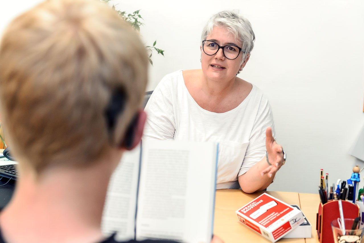Eine Mitarbeiterin des Fachdienstes fördert einen Schüler in seinem Textverständnis