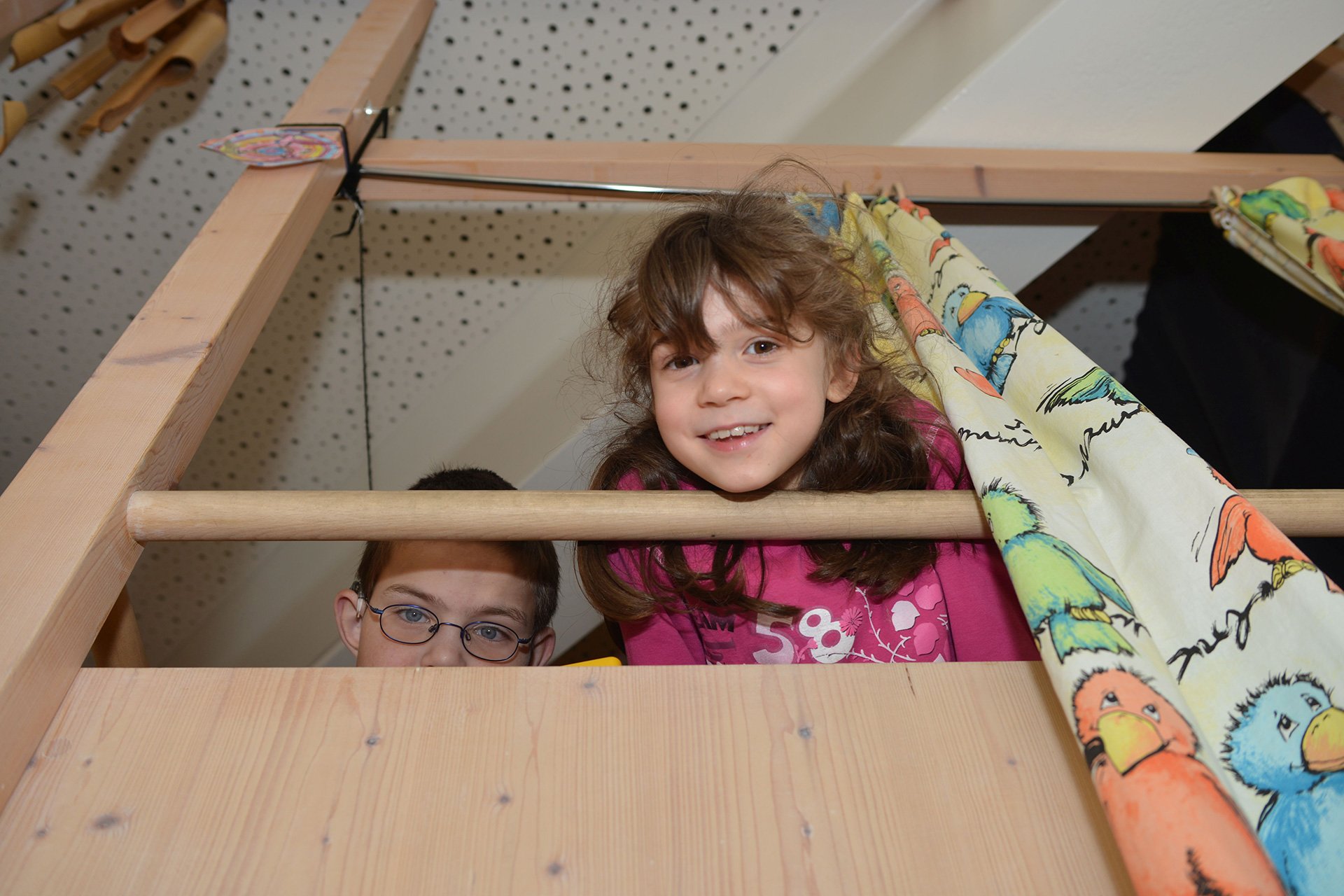 Zwei Kinder schauen von ihrem Lieblingsplatz aus nach unten in die Kamera