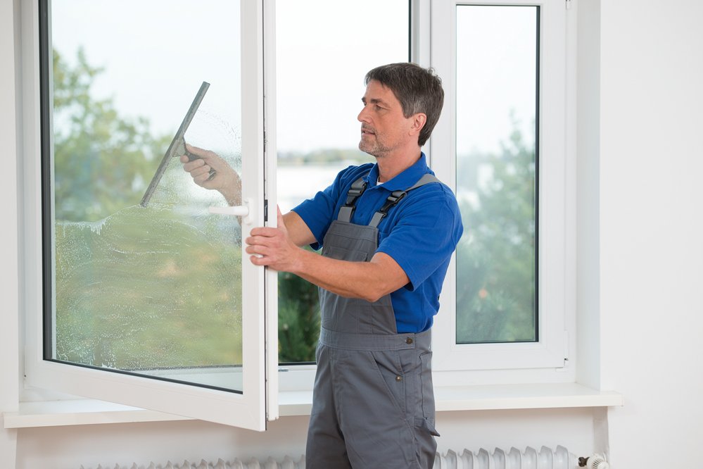 Einmal im Quartal werden die Fenster gereinigt Mann mittleren Alters beim Fensterputzen