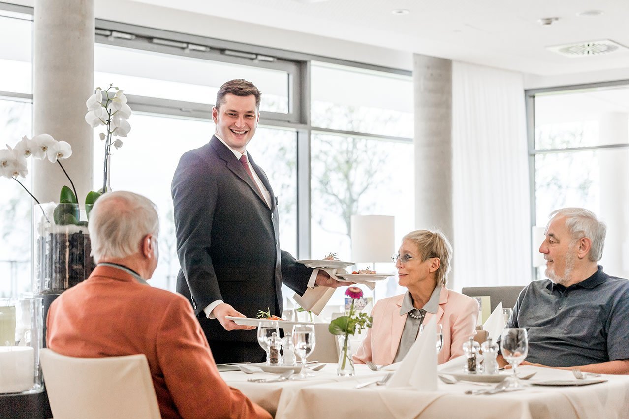 Persönlicher Service wie im Restaurant Kellner serviert Gästen am gedeckten Tisch