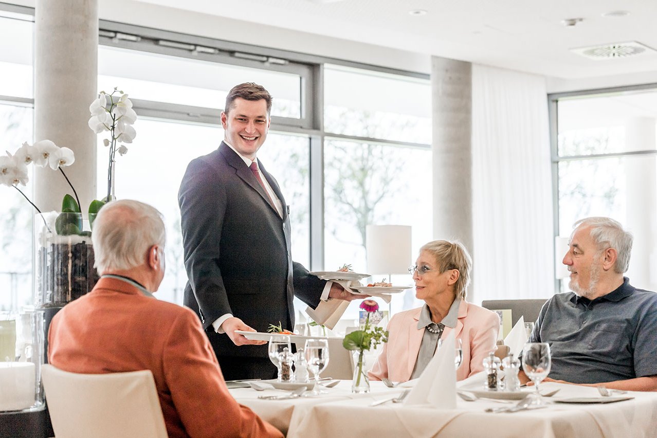 Kellner serviert Gästen am gedeckten Tisch