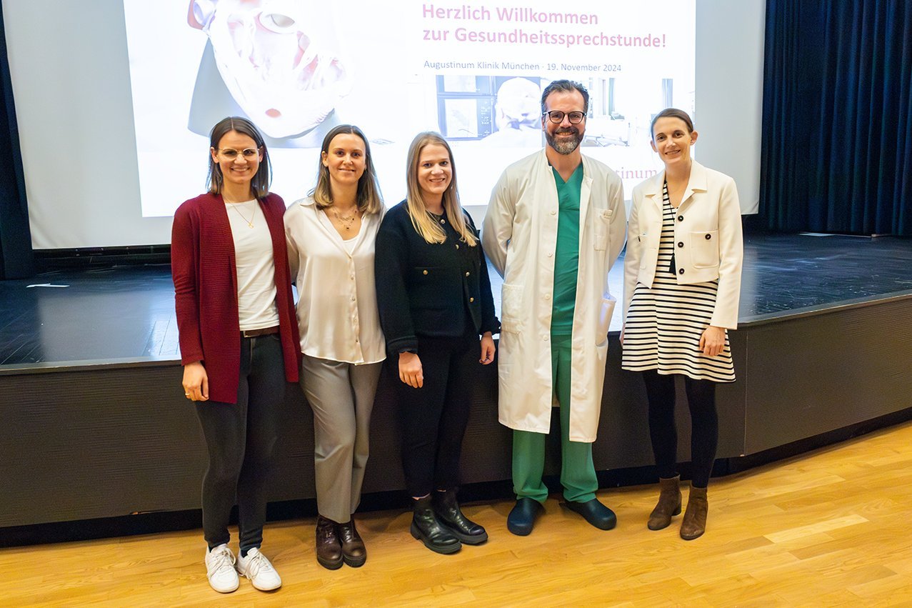 Augustinum Klinik Herzwochen Ein Gruppenbild der Referentinnen zusammen mit dem Veranstaltungsleiter vor einer Bühne