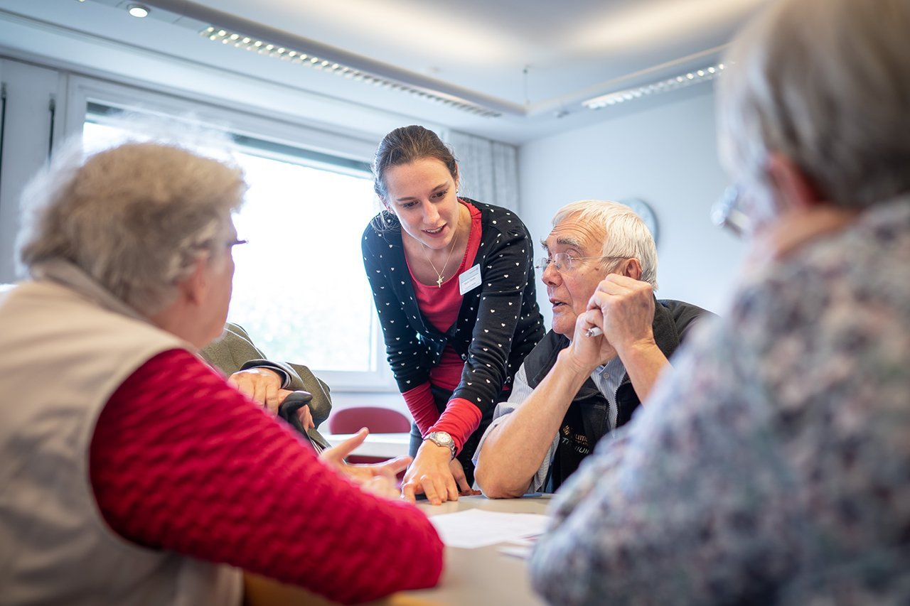 Eine Mitarbeiterin des Augustinum erklärt etwas den Senior*innen 