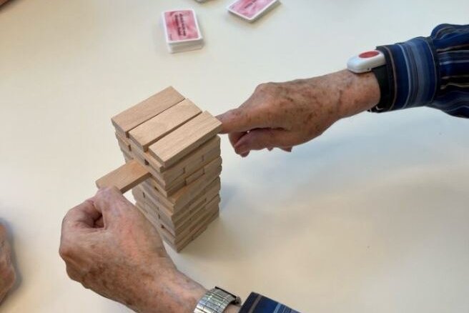 Augustinum Tagespflege Spiele Ein*e Senior*in und ein*e Mitarbeiter*in des Augustinum spielen gemeinsam Jenga