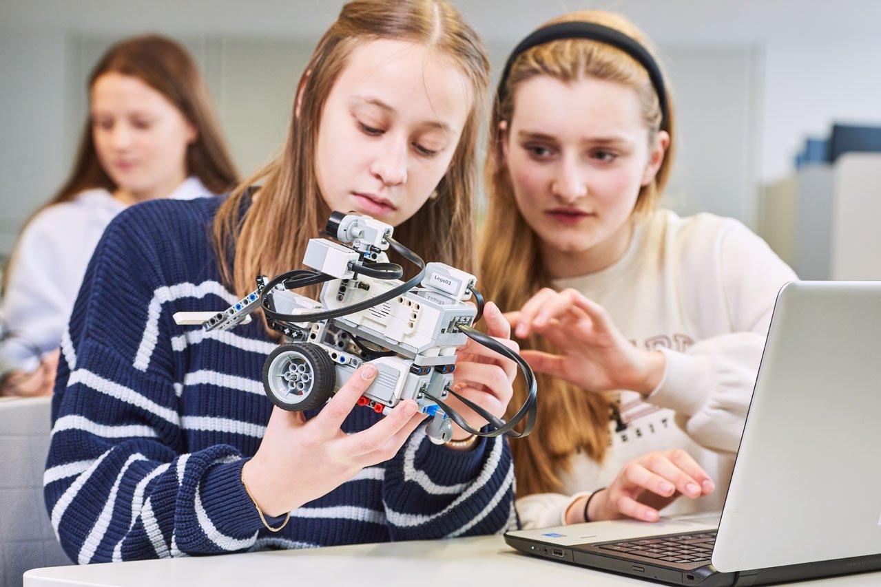 Robotik Zwei Schülerinnen überprüfen ihren Roboter im Fach Robotik