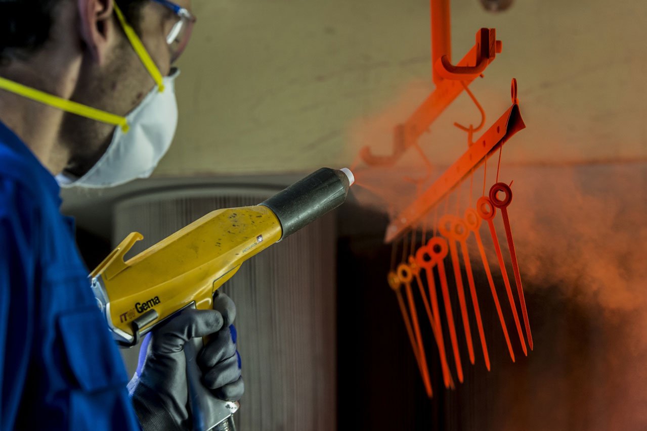 Pulverbeschichtung Ein Mann bespritzt ein Metallteil mit einer Pulverbeschichtungspistole