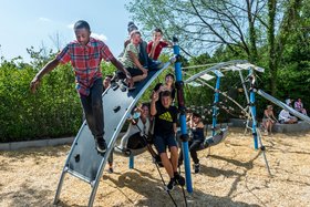 Augustinum Tagesstätte Olschewskibogen Spielplatz Kinder und Jugendliche sitzen auf einem Klettergerüst