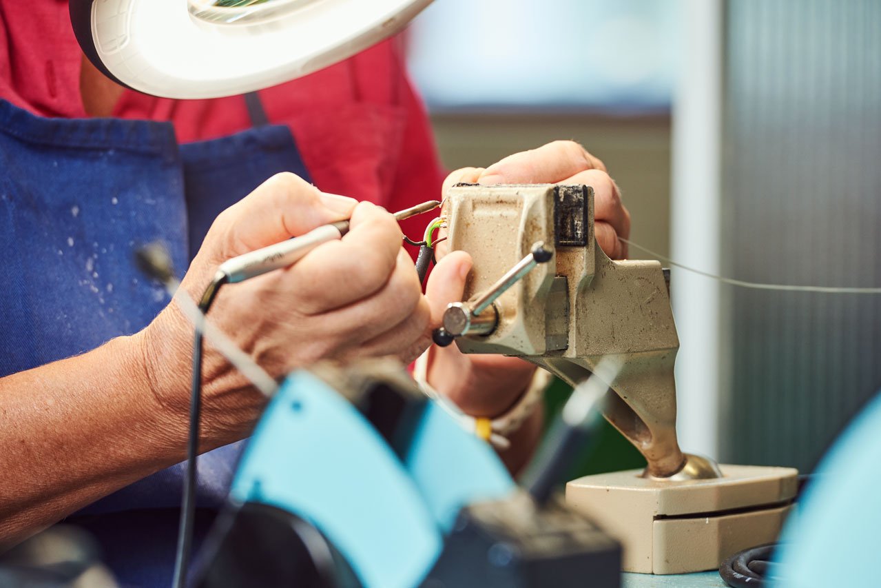 Ein*e Klient*in lötet Kabel im Bereich Kabelkonfektionierung