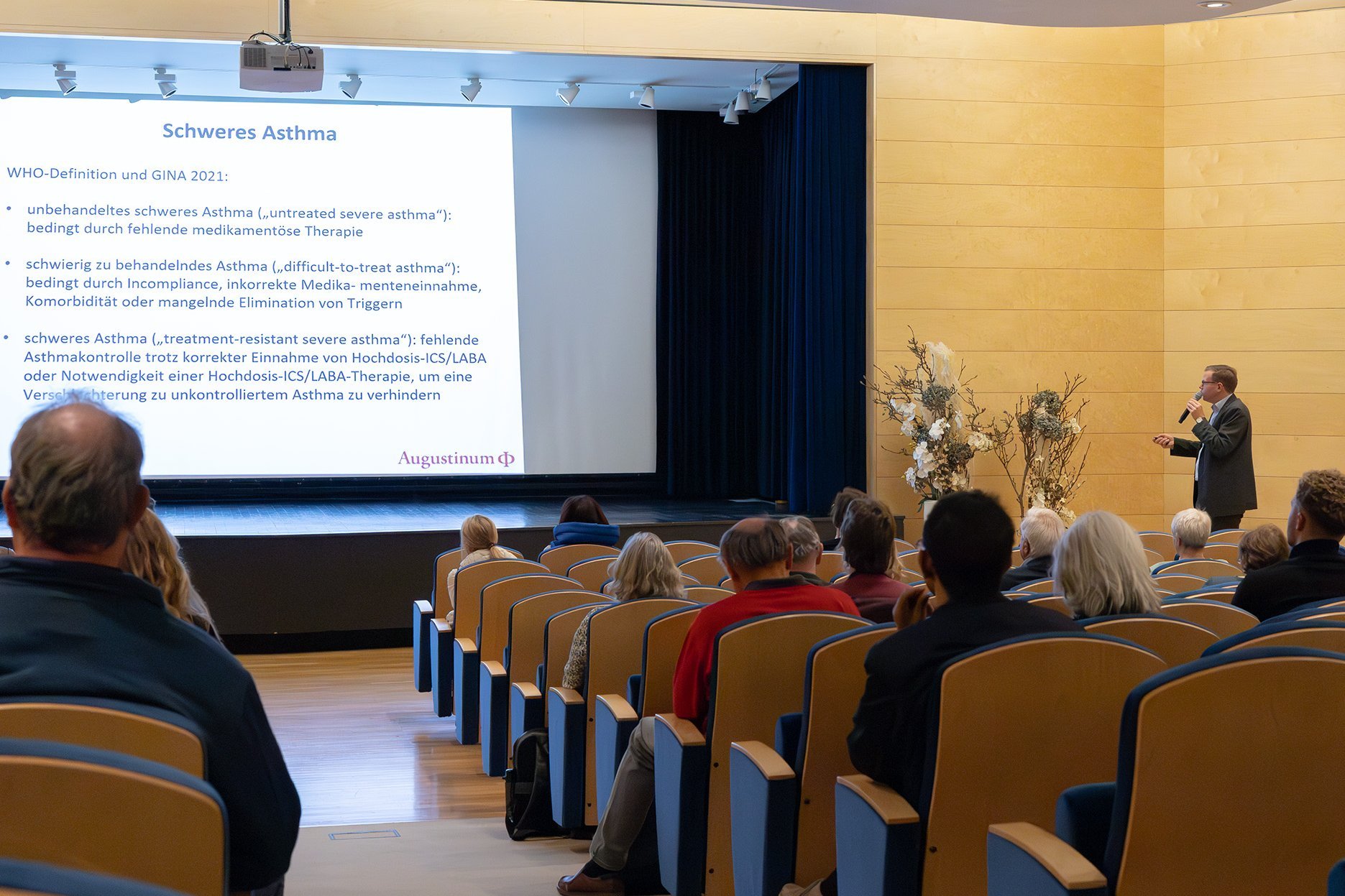 Die Besucher*innen sitzen im Theatersaal und hören dem Vortrag von Dr. Werner von Wulffen zu