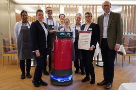 Augustinum Magazin Abräum-Roboter Service-Mitarbeiter*innen und der Geschäftsführer des Augustinum Kassel überreichen dem Abräum-Roboter eine Urkunde