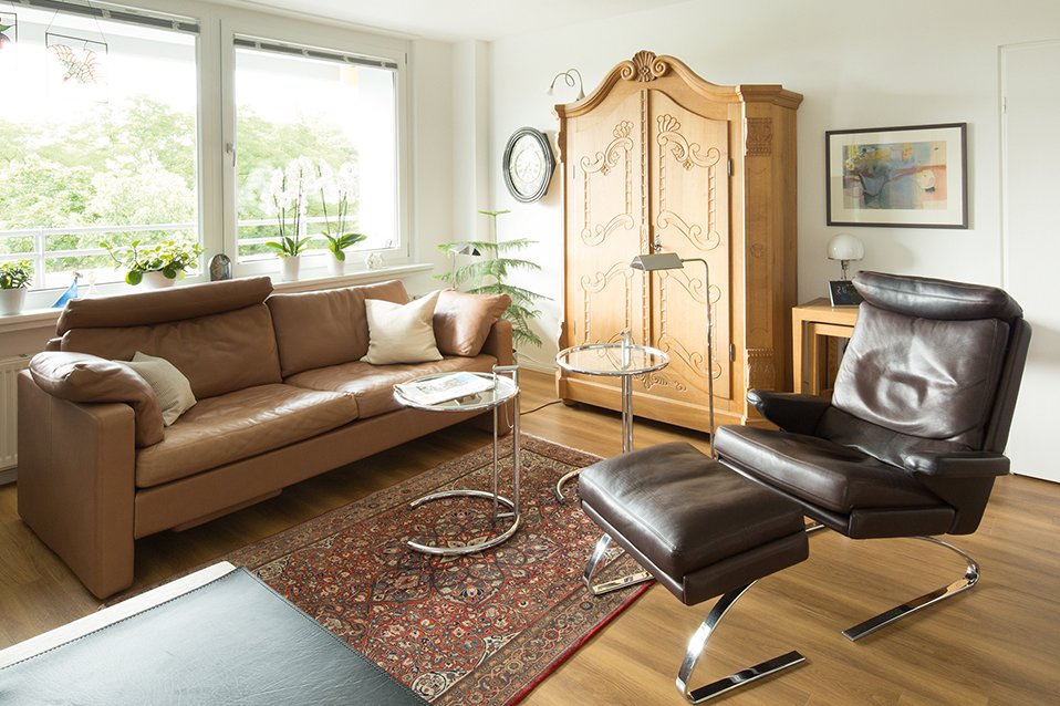 Ein Wohnbereich mit Couch, Sessel und Schrank