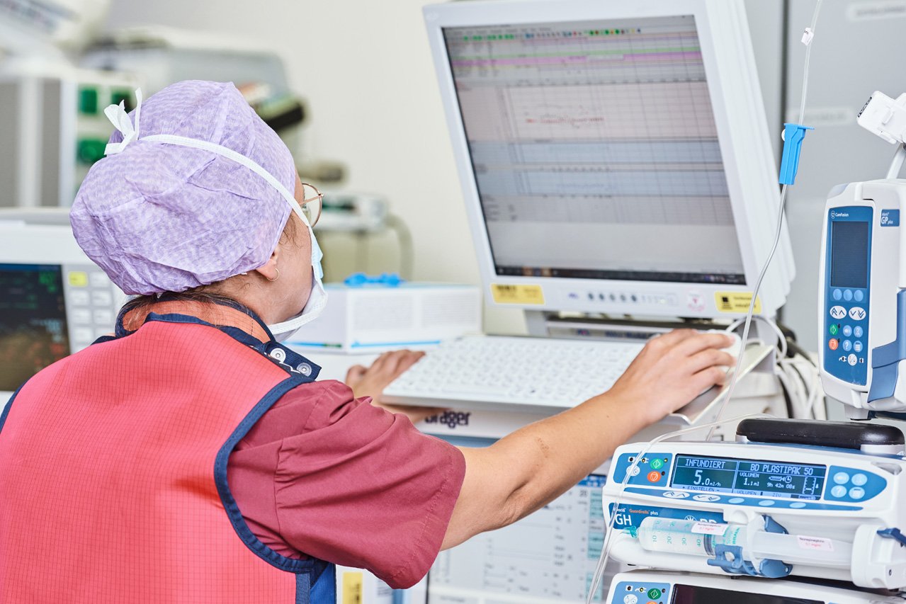 Überwachung der Vitalfunktionen Eine OP-Pflegerin kontrolliert während eines Eingriffs am Monitor die Werte eines Pateinten