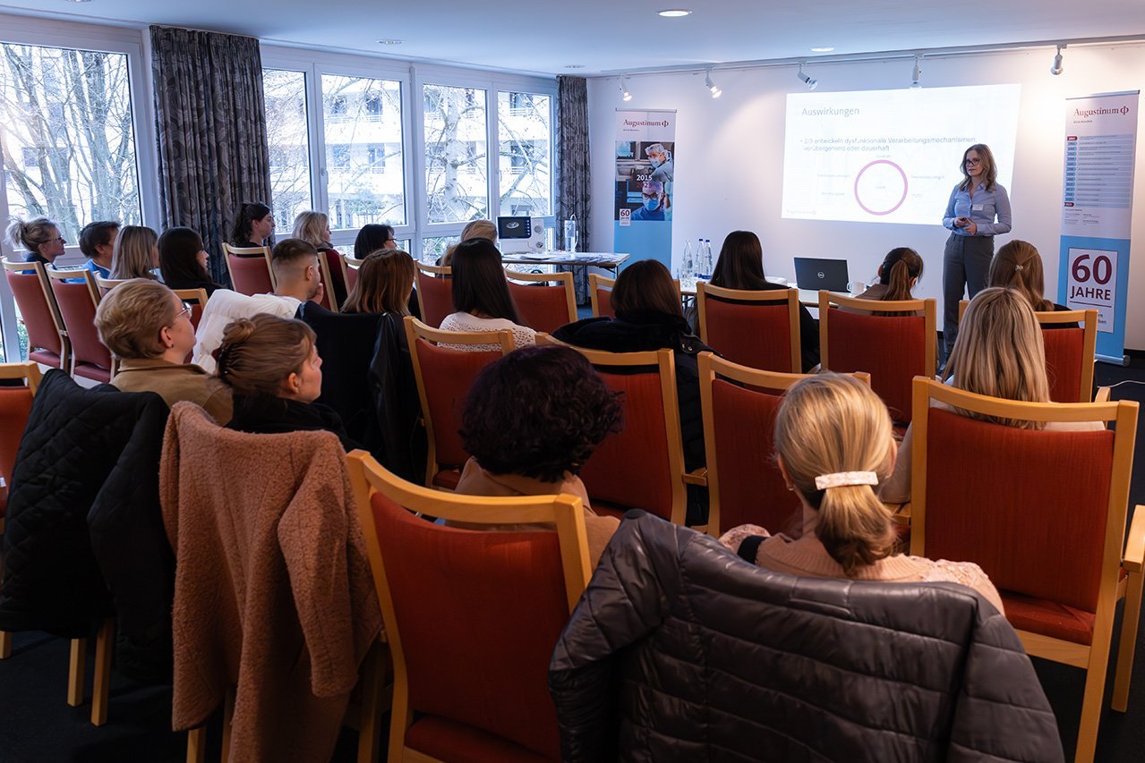 Augustinum Klinik Symposium Niehaus Die besetzten Stühle bei einem Workshop von hinten, wobei die Teilnehmer*innen auf Julia Niehaus schauen, die vor ihnen einen Vortrag hält