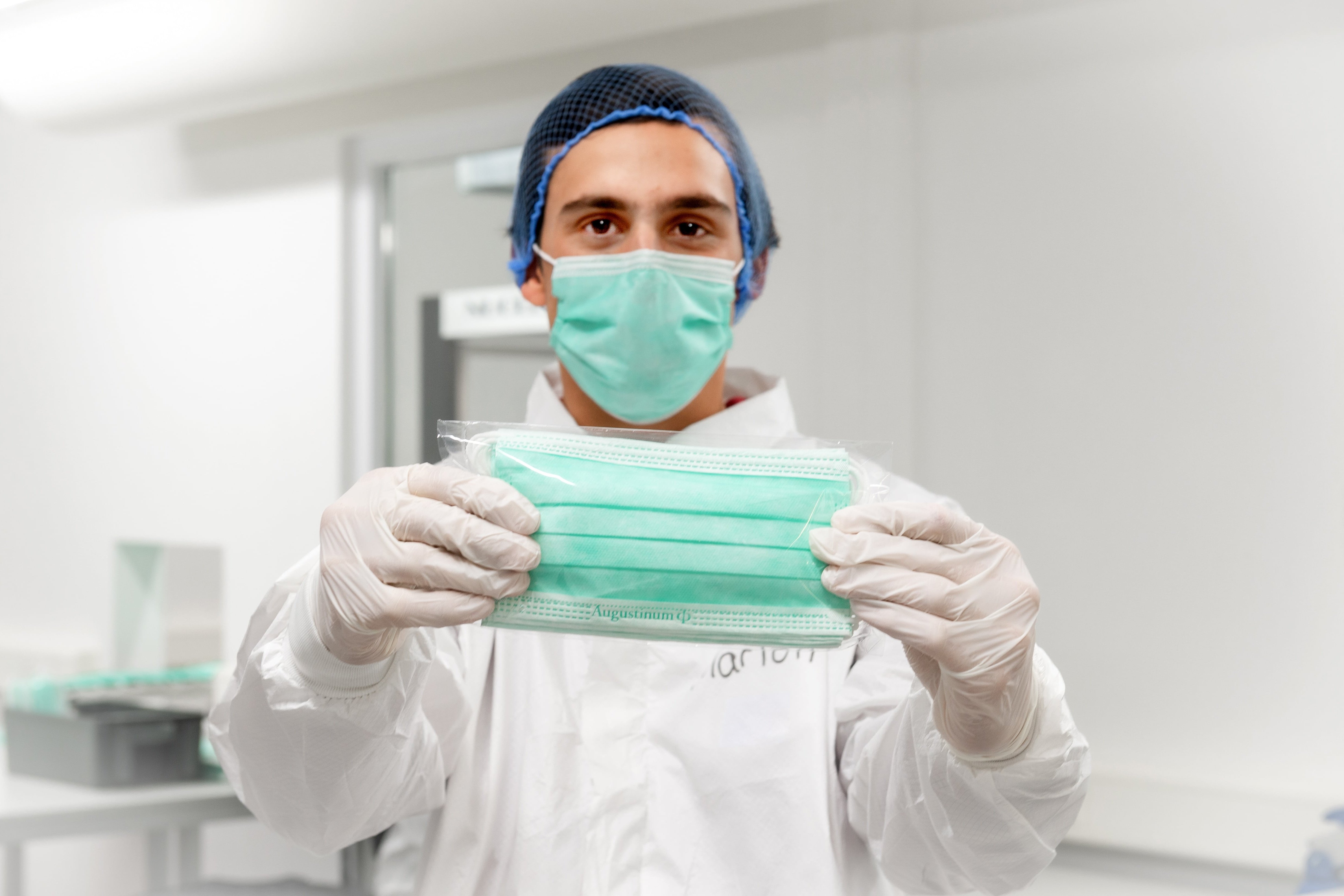 Ein Klient hält eine in den Augustinum Werkstätten produzierte medizinische Maske hoch
