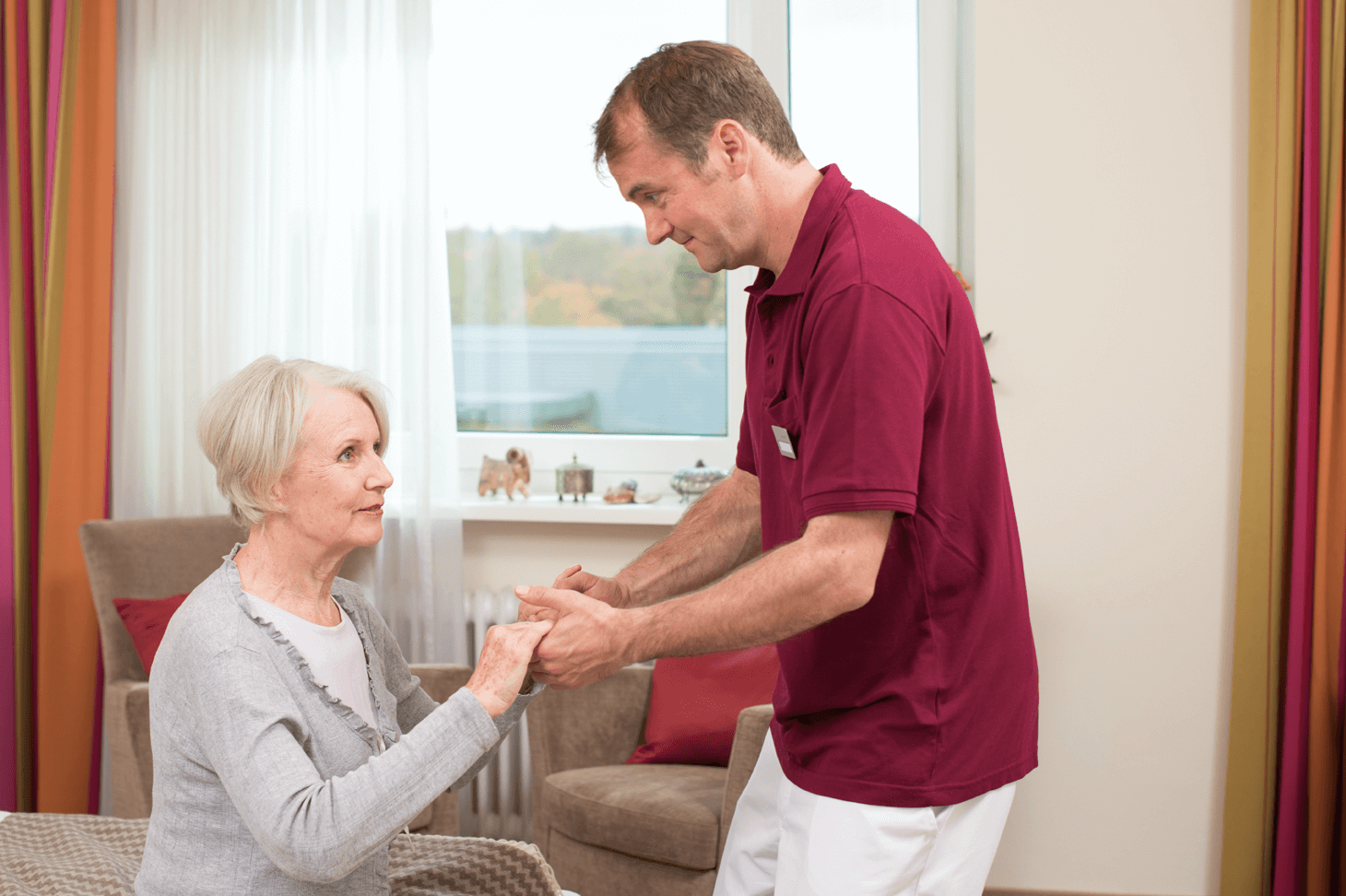 Pfleger hilft älterer Dame beim Aufstehen