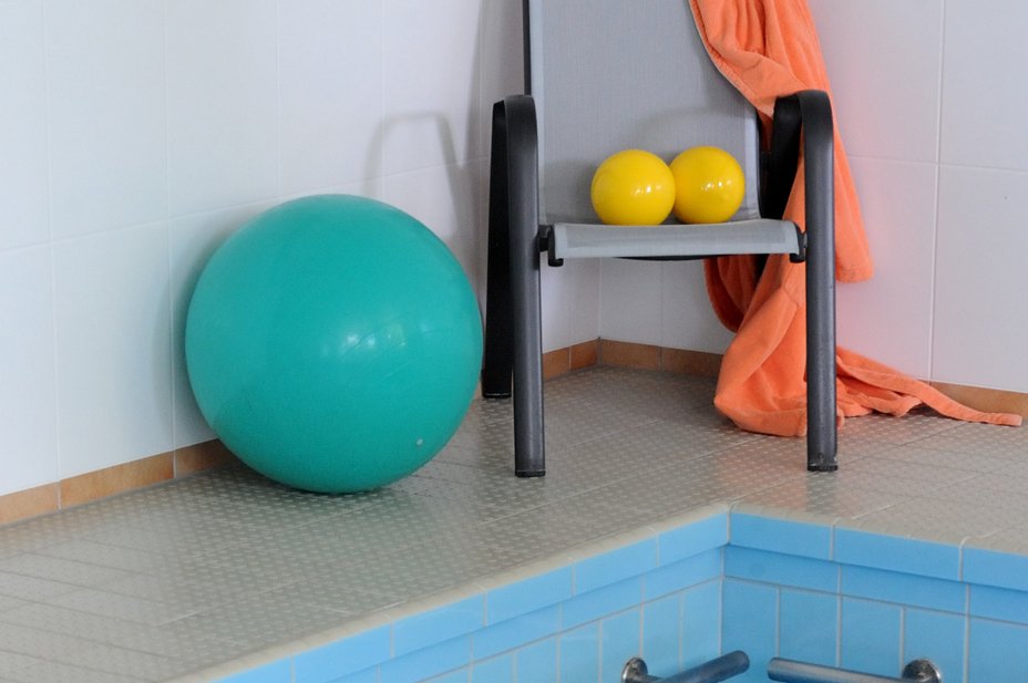 Augustinum Seniorenresidenzen Wassergymnastik Ein großer Gymnastikball und zwei kleine Bälle auf einem Stuhl am Schwimmbeckenrand