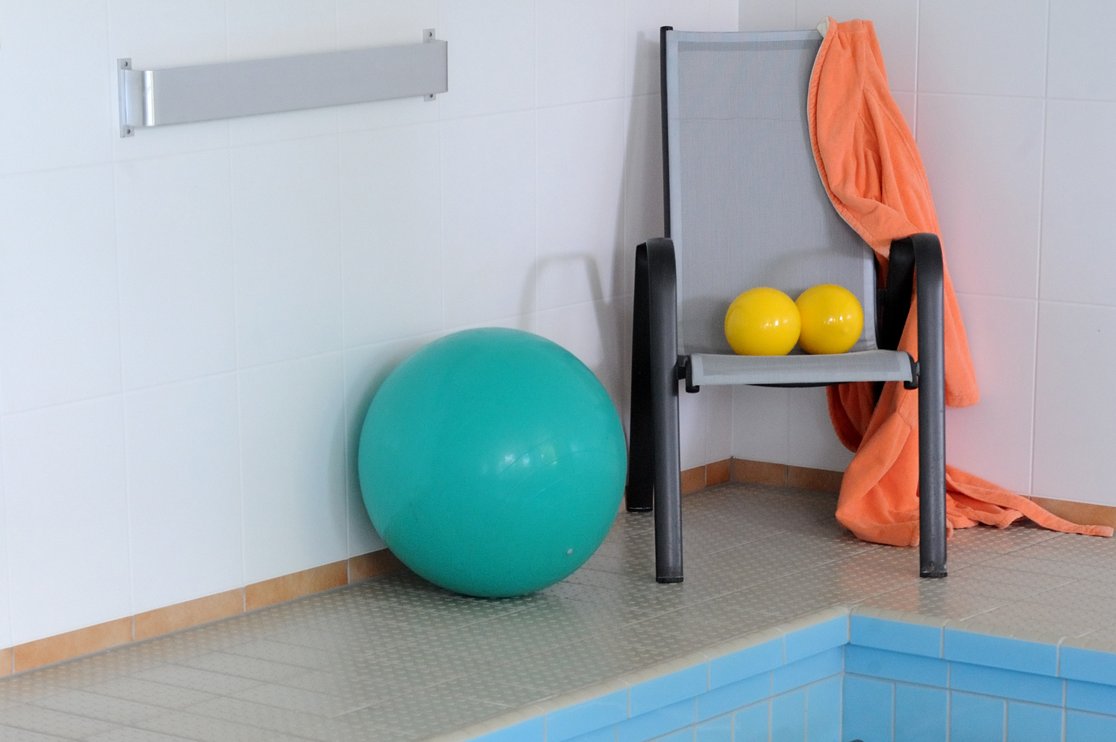 Gymnastikbälle und Stuhl am Rand eines Schwimmbeckens