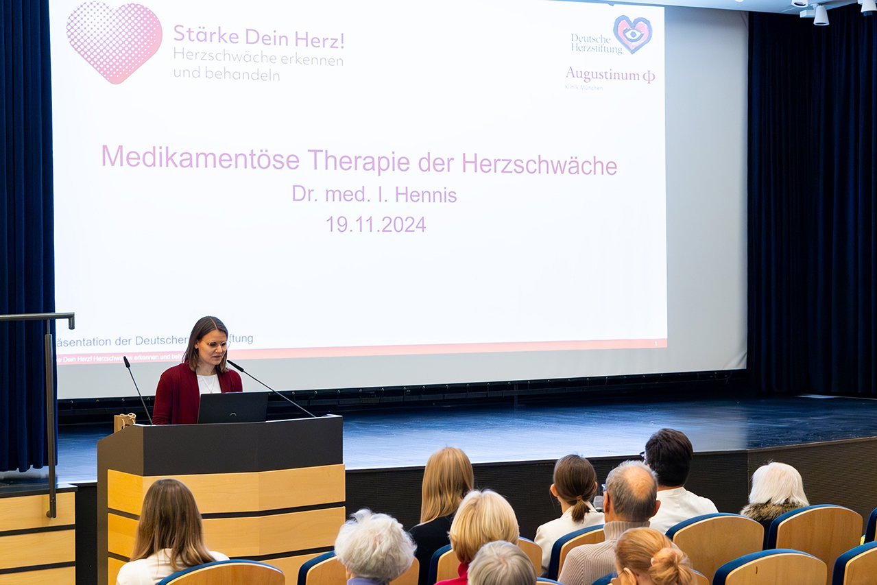 Augustinum Klinik Herzwochen Hennis Dr. Irina Hennis steht vor dem Publikum im Theatersaal und hält einen Vortrag zum Thema "Medikamentöse Therapie der Herzschwäche"