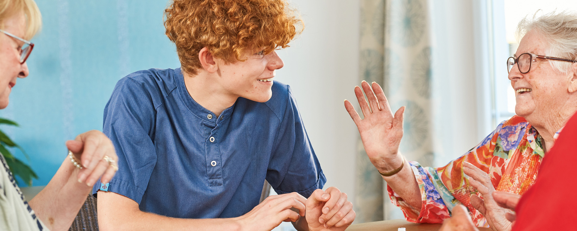 Augustinum Pflege Header Ein Pfleger des Augustinum unterhält sich mit zwei Seniorinnen