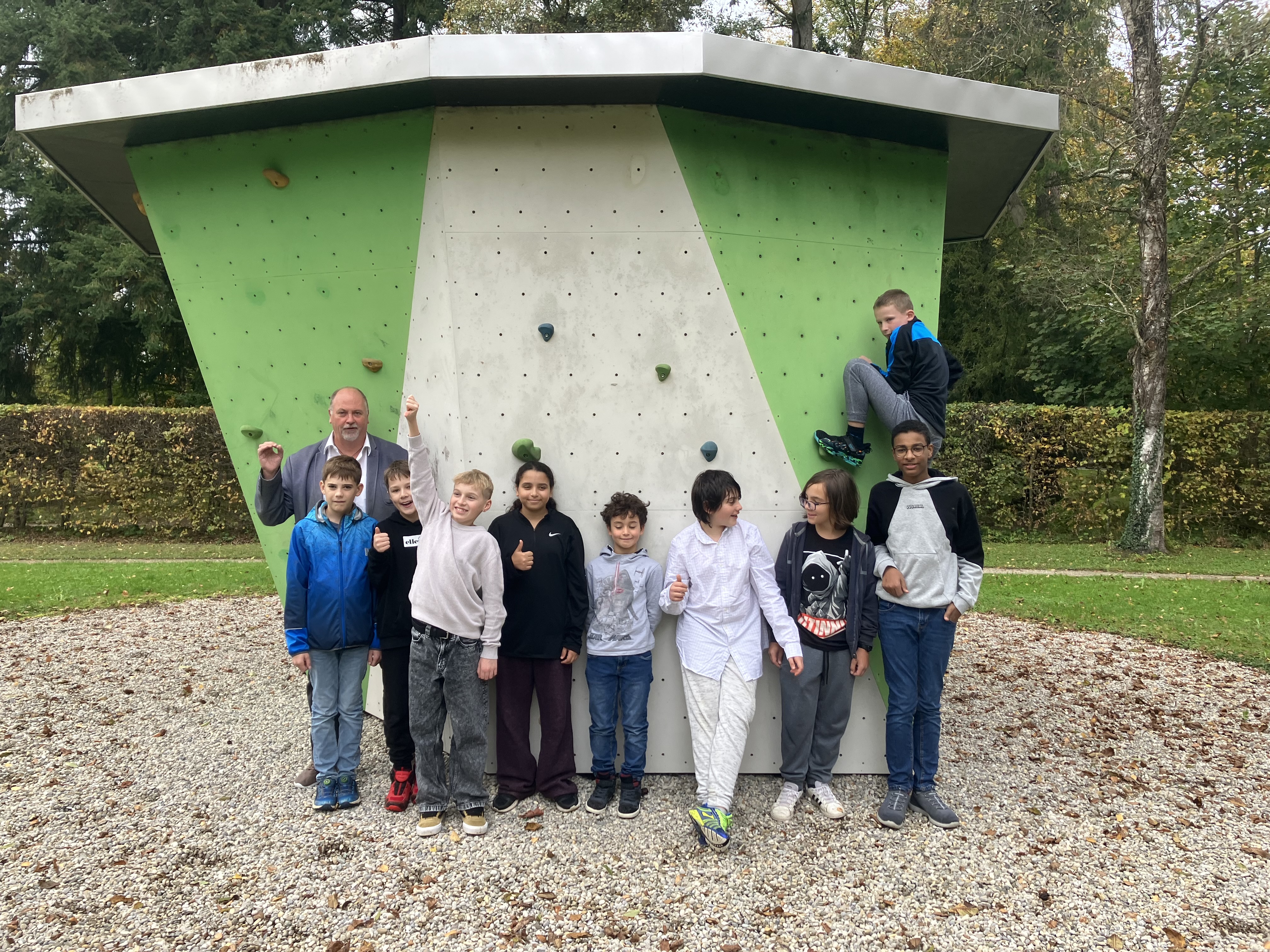 Augustinum Fördermagazin Boulderblock Ein Erwachsener und Schüler*innen stehen vor einer Boulderwand im Freien